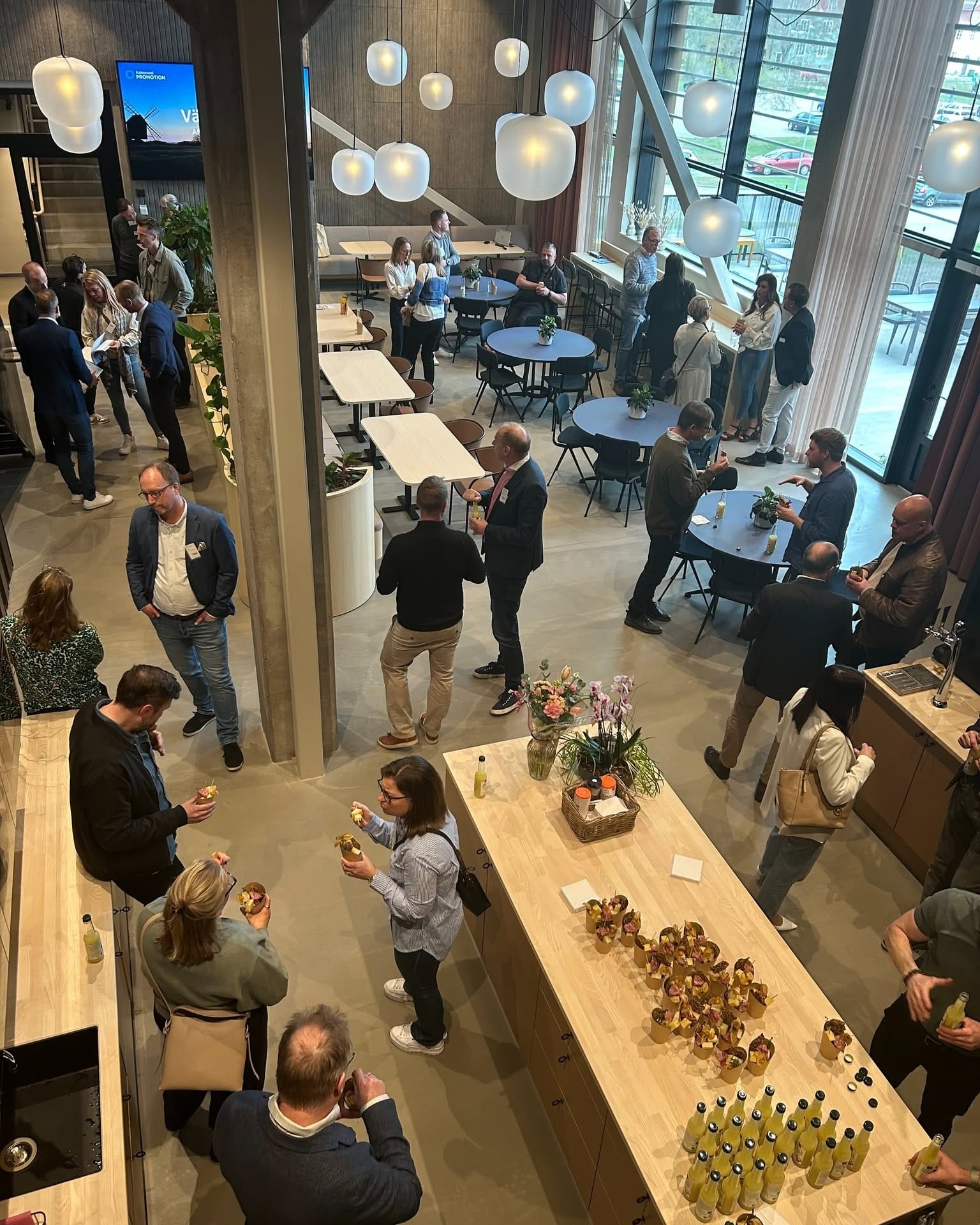 Nätverksträff i en modern lounge med Kalmarsund Promotion på skärmen